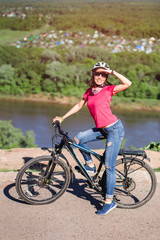 Young woman cycling on a clear blue day, with sunglasses and helmet.