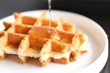 Tasty waffles with honey on plate