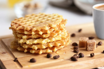 Tasty waffles with coffee on cutting board