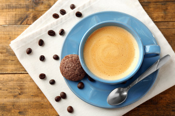 Cup of coffee with cookie on wooden table