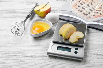 Making apple pie. Using digital kitchen scales on wooden table. Cooking apple cake concept