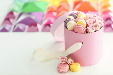 Tasty macaroons in box on colourful blurred background