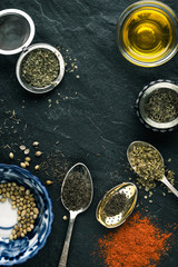 Spices, paprika, spoon, butter, ceramic plate on a black slate
