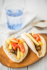 Gyros, a glass of water, dzatziki in a gravy boat on a wooden st
