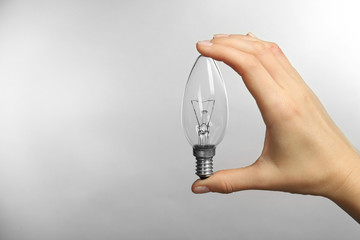 Woman hand holding bulb on grey background