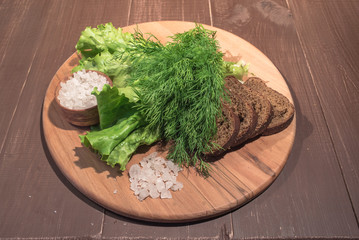 Lettuce and dill on wood plate with rye bread and sea salt


