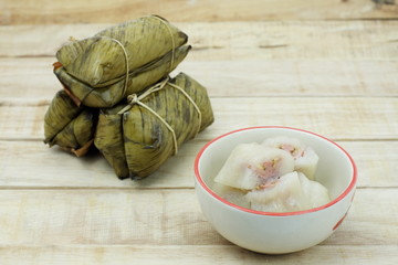 Bananas with Sticky Rice in small ceramic bowl on wooden background. Glutinous rice steamed in banana leaf. Traditional Thai food style Thai name is Khao Tom Mat.