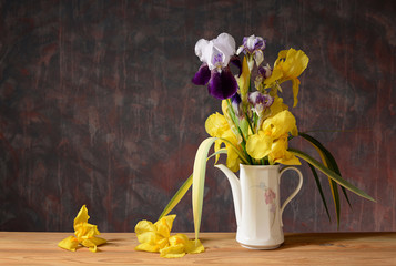 Yellow iris in a ceramic vase on a wooden table
