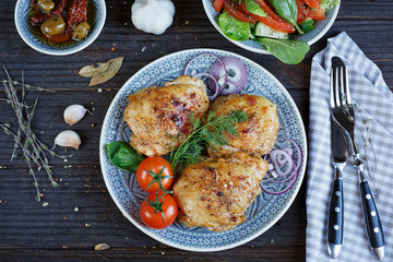 Roasted chicken and vegetables on dark wooden background