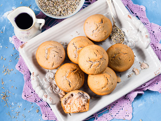Lavender muffins with ingredients - lavender syrup, milk and lavender flowers on blue textured background. Top view