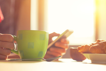 fresh breakfast with hot coffee and browsing smartphone in morni