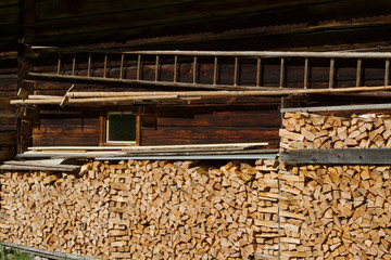 Firewood stacked by the alpine hut. Rustic farming scene.