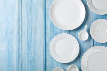 Empty plates and bowls on blue wooden background