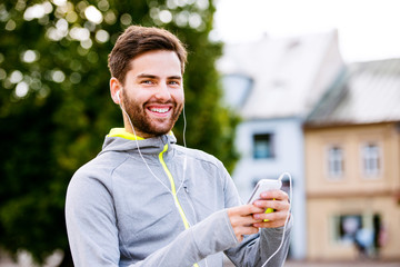 Young hipster runner in town with smartphone