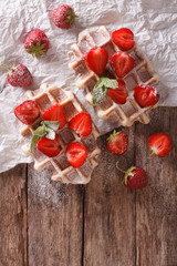 Belgian waffles with strawberries and powdered sugar close-up. Vertical top view

