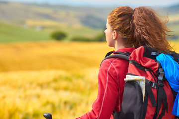 Tourist girl view of green wheat hills.