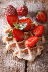 Belgian waffles with strawberries and powdered sugar close-up. vertical
