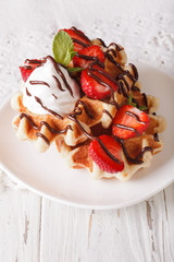 Belgian waffles with strawberries, whipped cream and chocolate close-up. vertical

