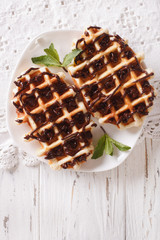 Belgian waffles with chocolate on a plate close-up. vertical top view
