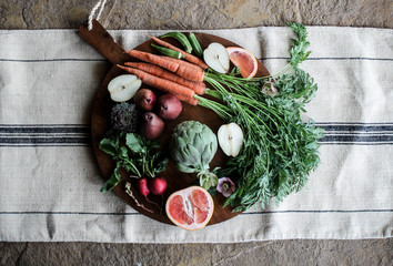 Selection of fruit and vegetables on wooden chopping board, overhead view