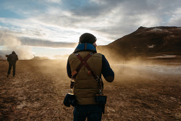 Rear view of man walking on geothermal site by mountain