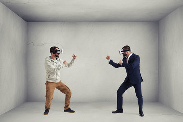 Fototapeta na wymiar Two men in virtual reality glasses in grey empty room