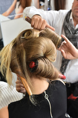 Fototapeta premium Hair curling process. Hairdresser woman curls her hair. Creating hairstyles hairdresser. Professional tool for creating curls