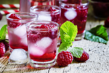 Sweet cocktail with raspberries, ice and soda, vintage wooden ba