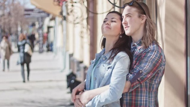 Cute girl and boy with long hair posing on street, looking on attraction