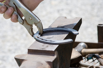 Shaping a Horsehoe – A blacksmith farrier places a horseshoe on an anvil in preparation of shaping it to fit the horse's hoof.