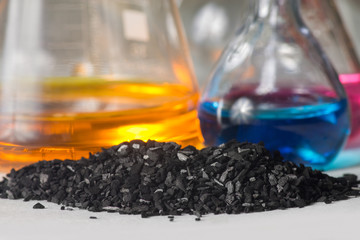 Charcoal fines against background of flasks with colored liquids
