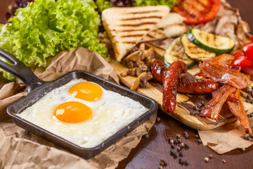 English breakfast with fried eggs, sausages, bacon, vegetable, bread and spices