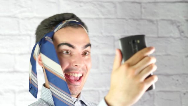 Businessman looking intoxicated or drunk taking funny selfies with his smartphone device.