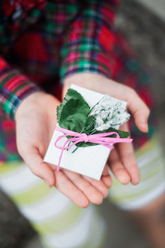 Person holding small posy with bow and paper