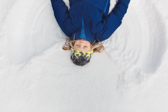 Boy making snow angel in snow, overhead view