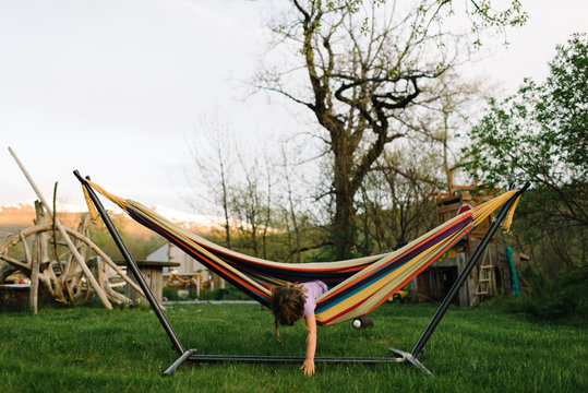 Young girl in hammock, leaning out to touch ground