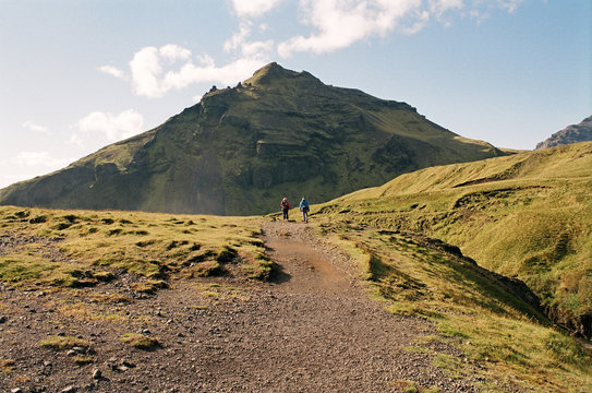 Hikers on a trail on a green mountain top in Iceland