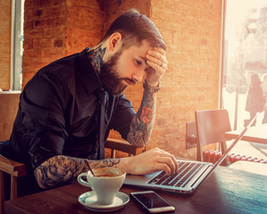 Toughtful bearded man using a laptop.