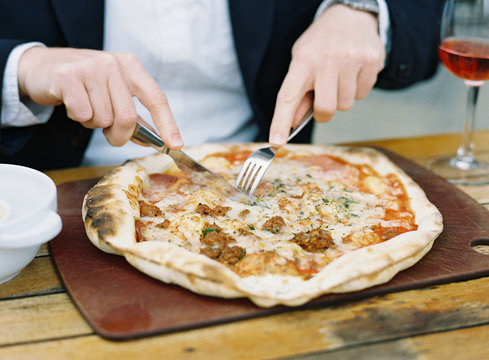 Man Cutting Pizza With Knife And Fork