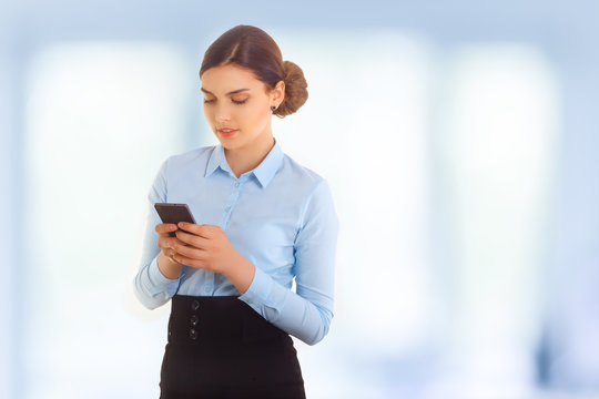 Businesswoman using smartphone over blue background. Wearing in blue shirt. Babette hairstyle.