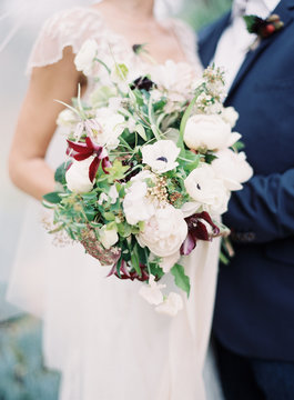 Cropped view of bride and groom holding bouquet