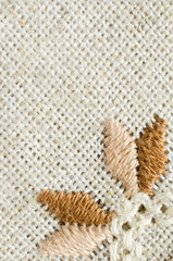 Embroidered fragment on flax by cotton threads. Macro embroidery texture flat stitch.