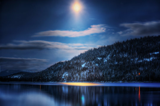 View of tree covered mountain by lake in moonlight