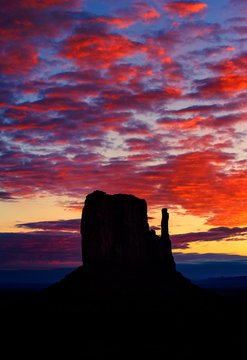 Silhouette of rock formation against dramatic orange sky