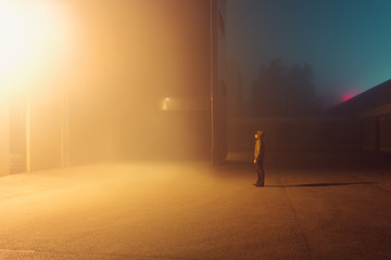 Man standing outside building in fog at night