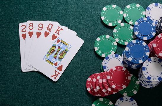 Casino chips and flush cards combination on the green table. Poker game concept
