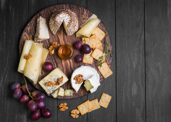 Assorted cheeses on round wooden board plate