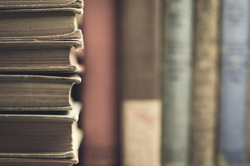 Vintage style stacked books with books in background 