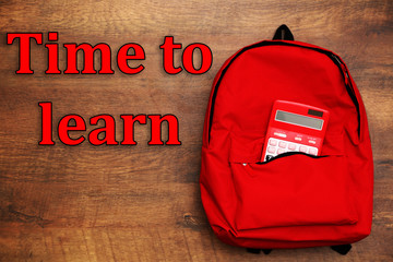 Backpack and calculator on wooden background