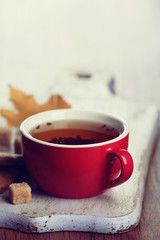 Cup of tea with autumn decor on wooden table.